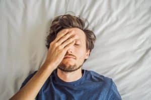 man laying on bed with face covered trying to gauge the heroin detox timeline