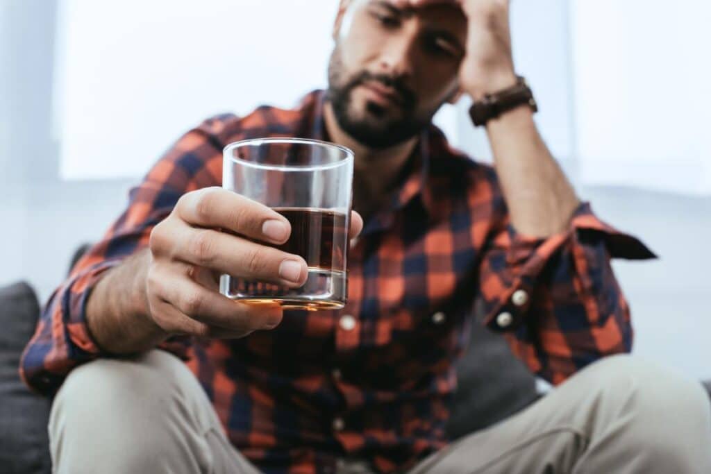 a man struggles with alcoholism with a drink in his hand