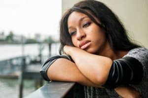 young woman just now understanding the stages of alcoholism as she leans against a balcony rail