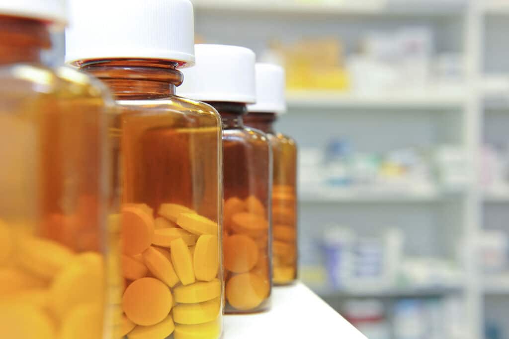close up of pill bottles on pharmacy shelf displaying opioid vs opiate drugs
