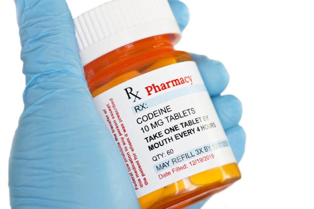 a close up of a prescription bottle of codeine in a doctor's gloved hand