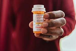 man in red shirt holding a prescription pill bottle for opioid