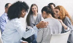 Addicted people comforting woman at psychotherapy session